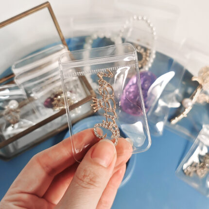 Close-up of a hand holding a small, high-transparency plastic ziplock bag with a brooch, showing our ready-to-ship blank jewelry packaging