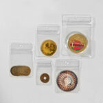 Clear PVC hanging hole ziplock bags protecting gold and silver commemorative coins.