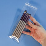 Hand holding a transparent PVC packaging resealable bag with cosmetic makeup brushes inside