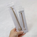 Hand holding a highly transparent PVC jewelry pudding bag displaying a pearl necklace