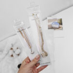 Retail ready clear PVC necklace packaging pudding pouches with hanging holes held in hand