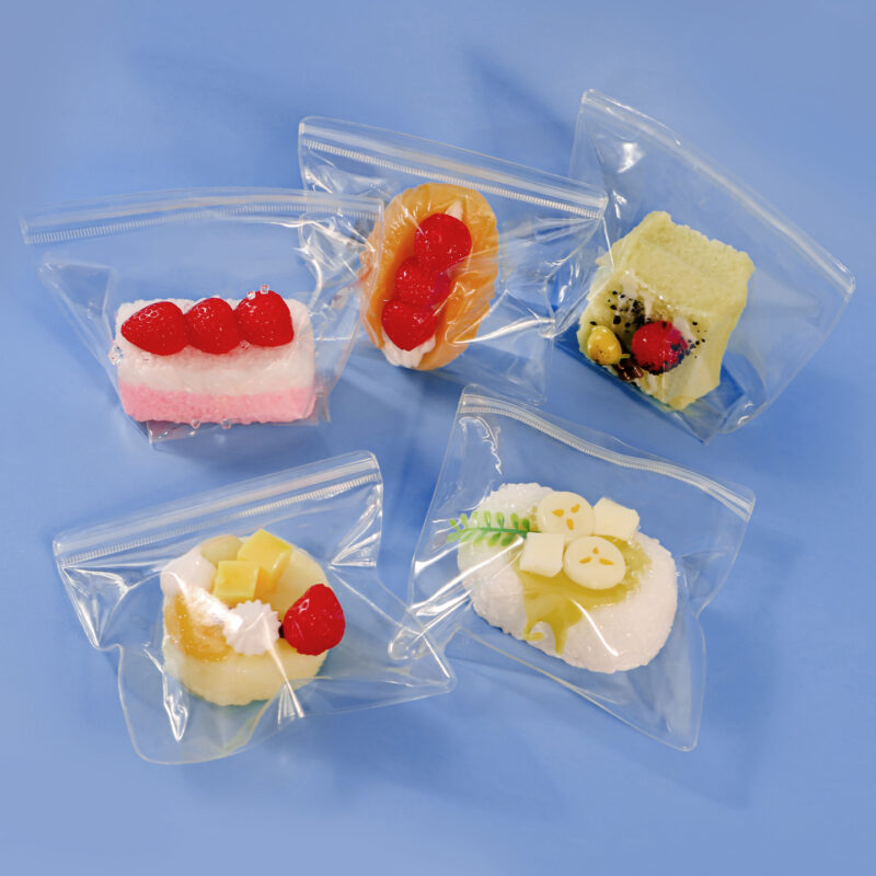 A variety of custom squishy toy packaging bags displaying colorful dessert squishies on a clean blue background.