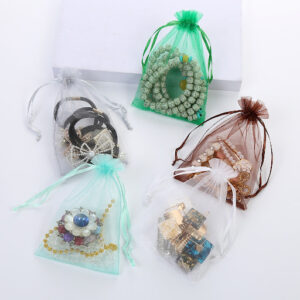 Colorful sheer organza bags packaging various jewelry like beads, brooches, and hair accessories for event favors.