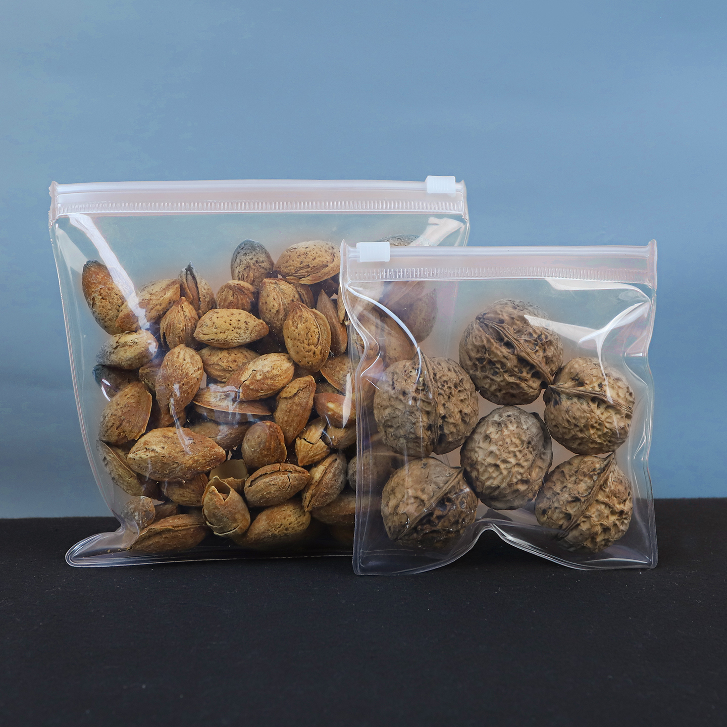 Close-up of transparent EVA zipper bags holding almonds and walnuts, highlighting the material's glass-like clarity and crack resistance.